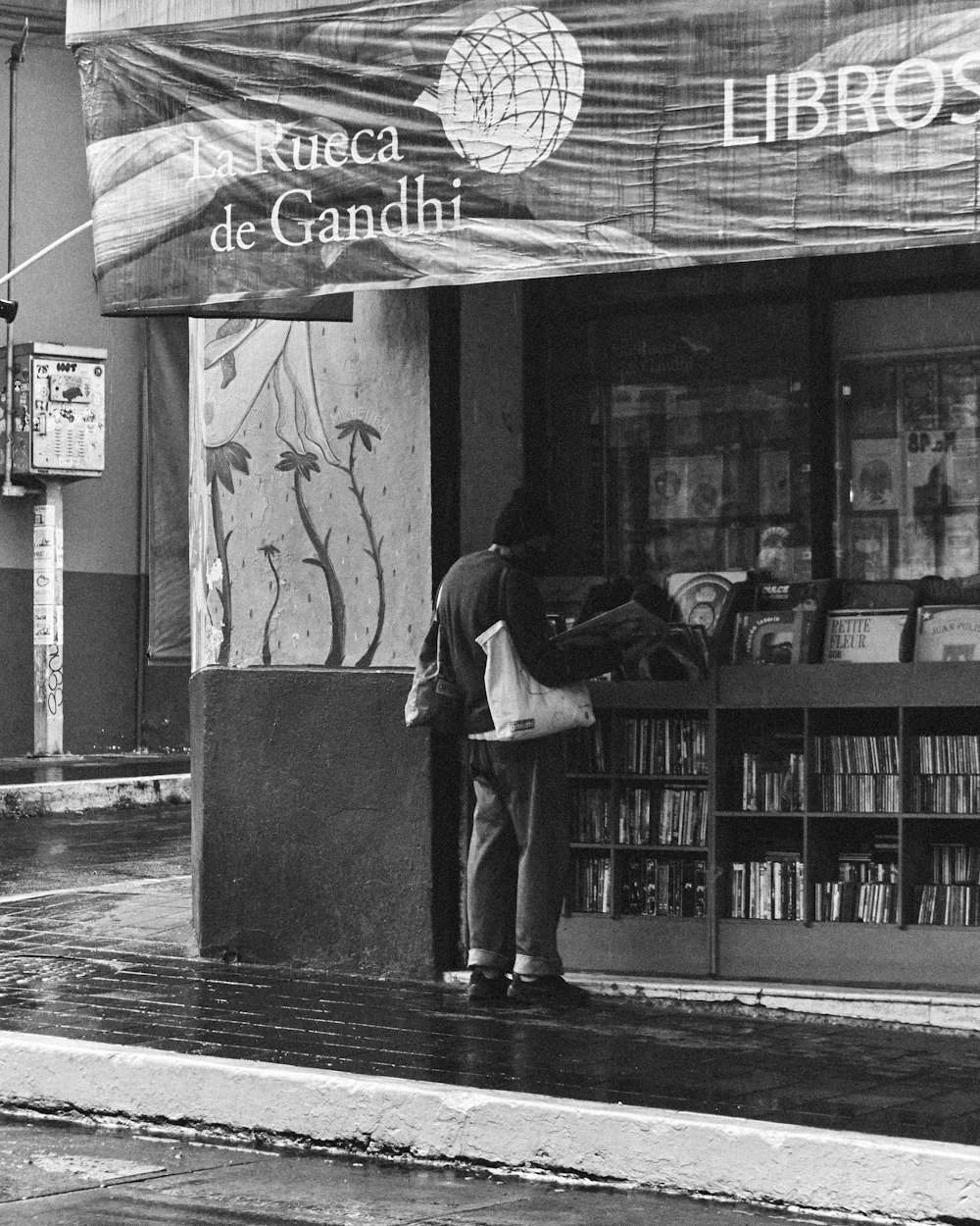 a black and white photo of a man standing in front of a book store