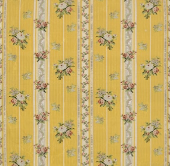 A floral patterned wallpaper featuring vertical yellow stripes with intricate floral bouquets and decorative elements in between. The flowers are arranged in small clusters with colors including white, pink, and green, adding a vintage charm to the design.