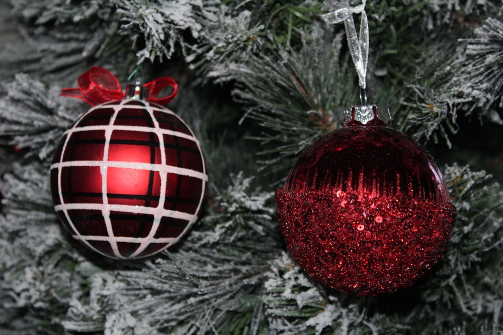 two red and white ornaments hanging from a christmas tree