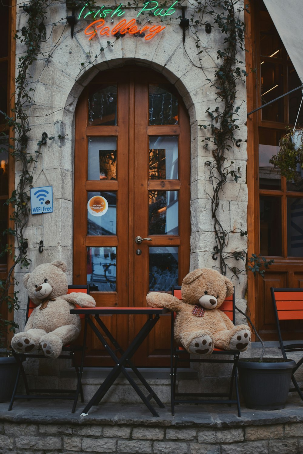 two teddy bears sitting at a table in front of a building