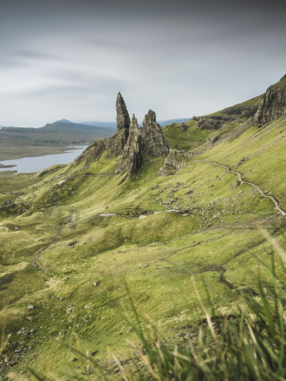 a grassy hill with a body of water in the distance