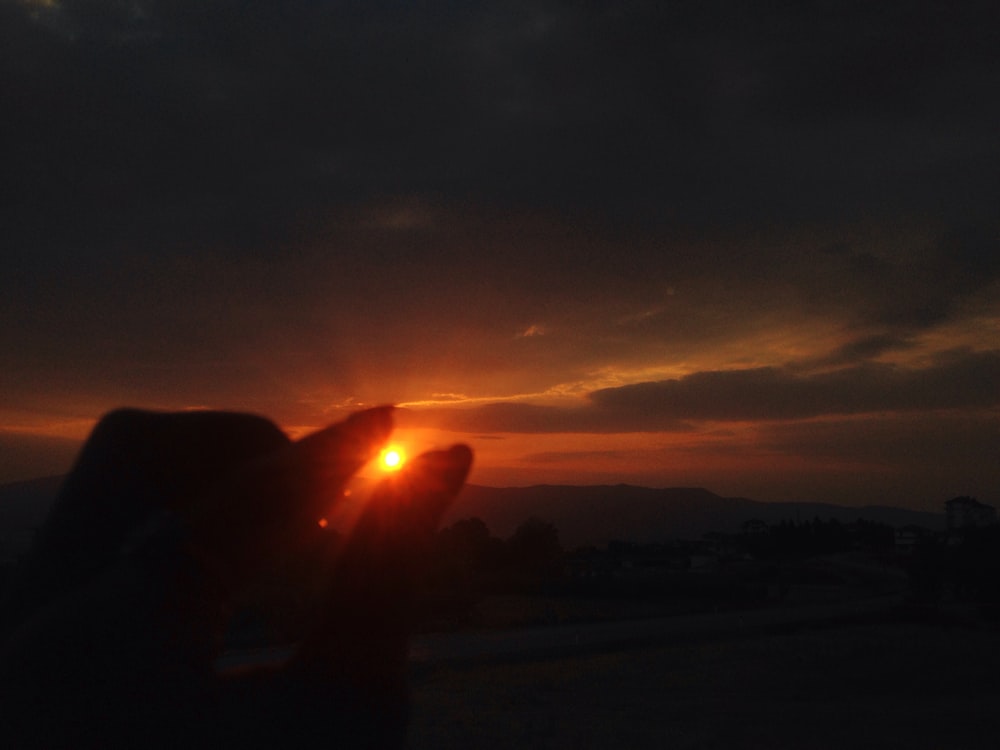 a person holding their hand up to the sun
