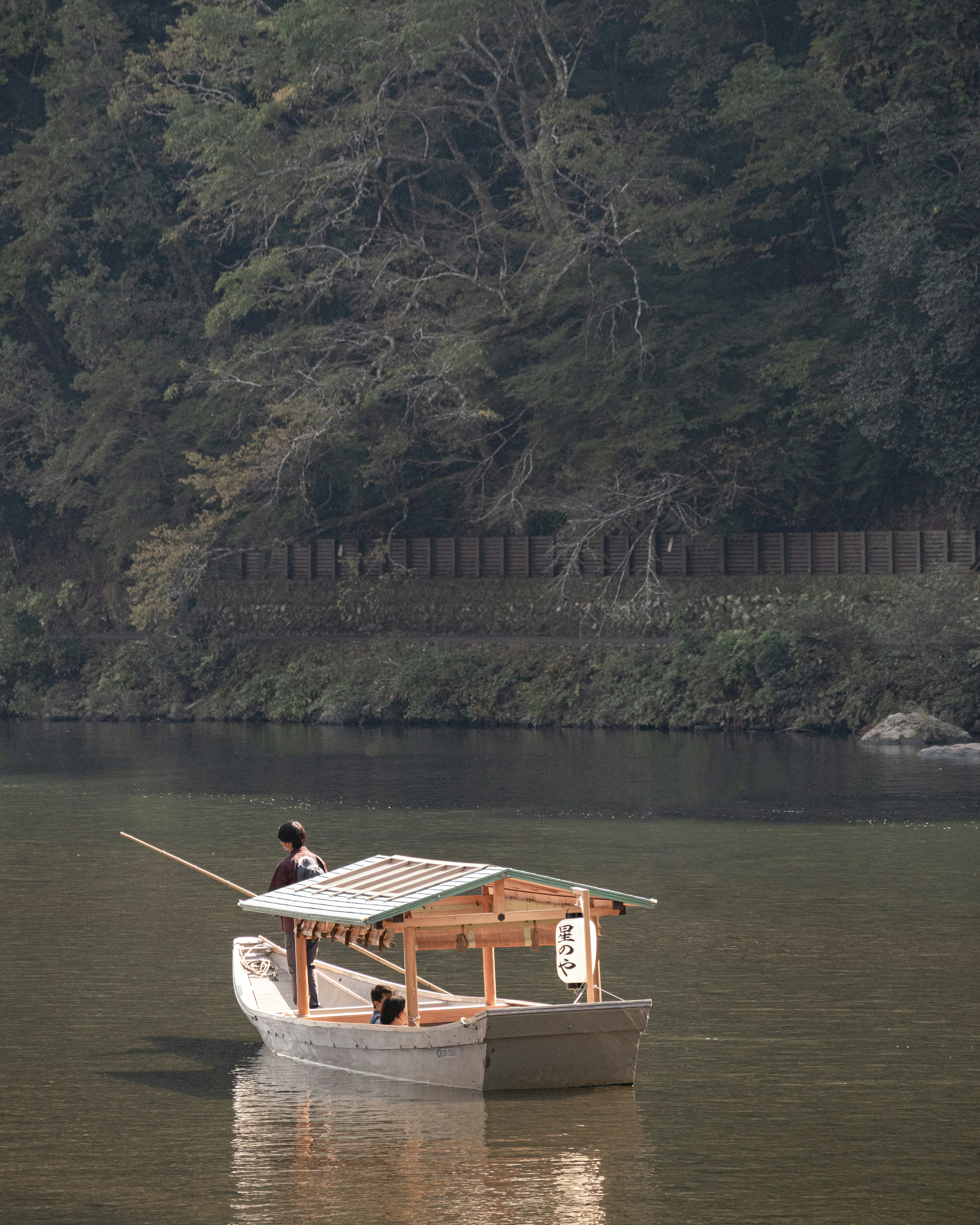 Small wooden boat drifting on the Hozu River near Arashiyama