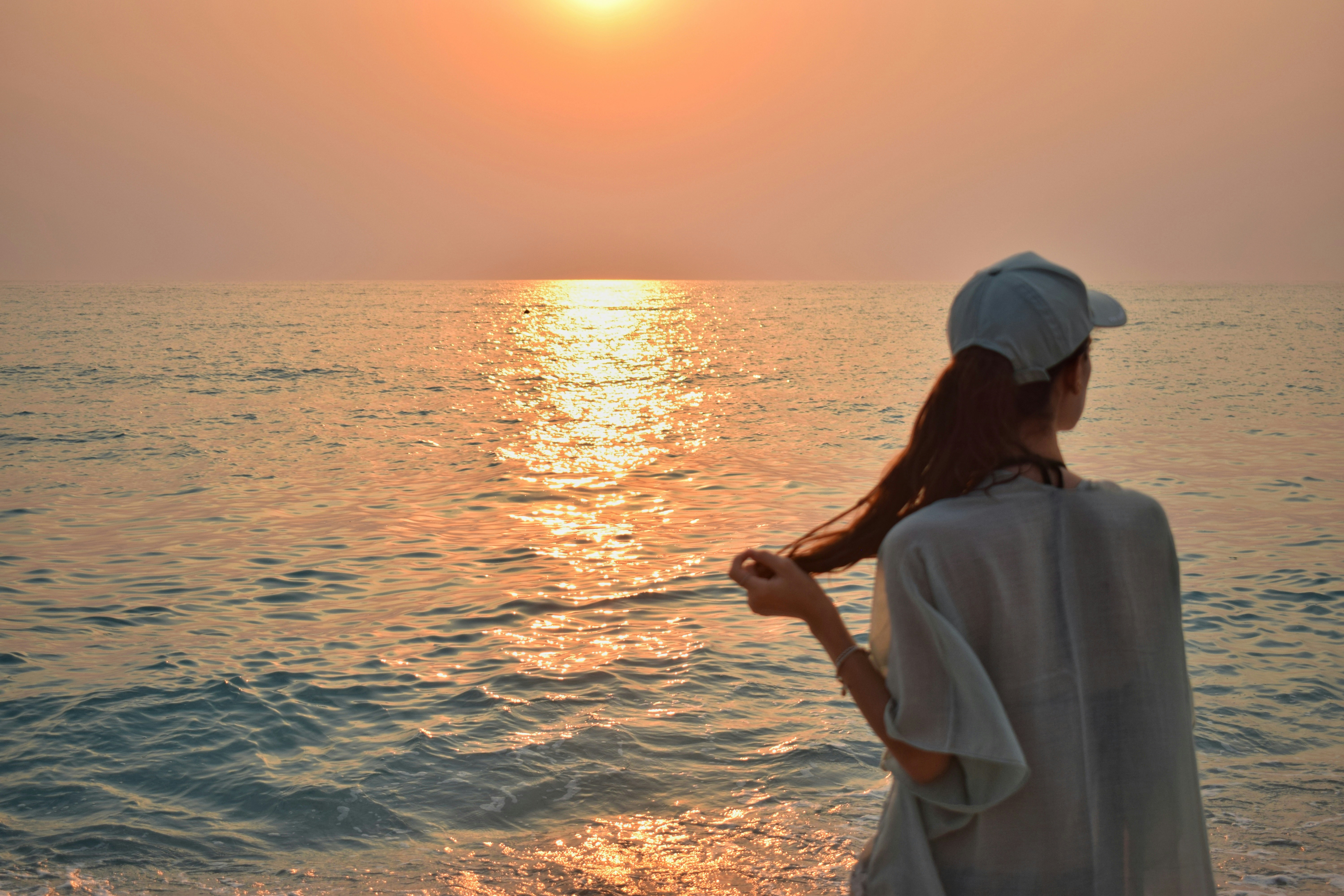 une femme debout sur une plage à côté de l’océan