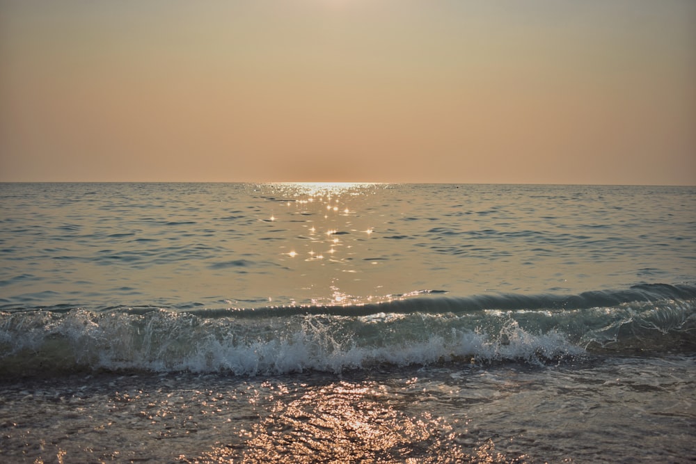 the sun is setting over the ocean waves