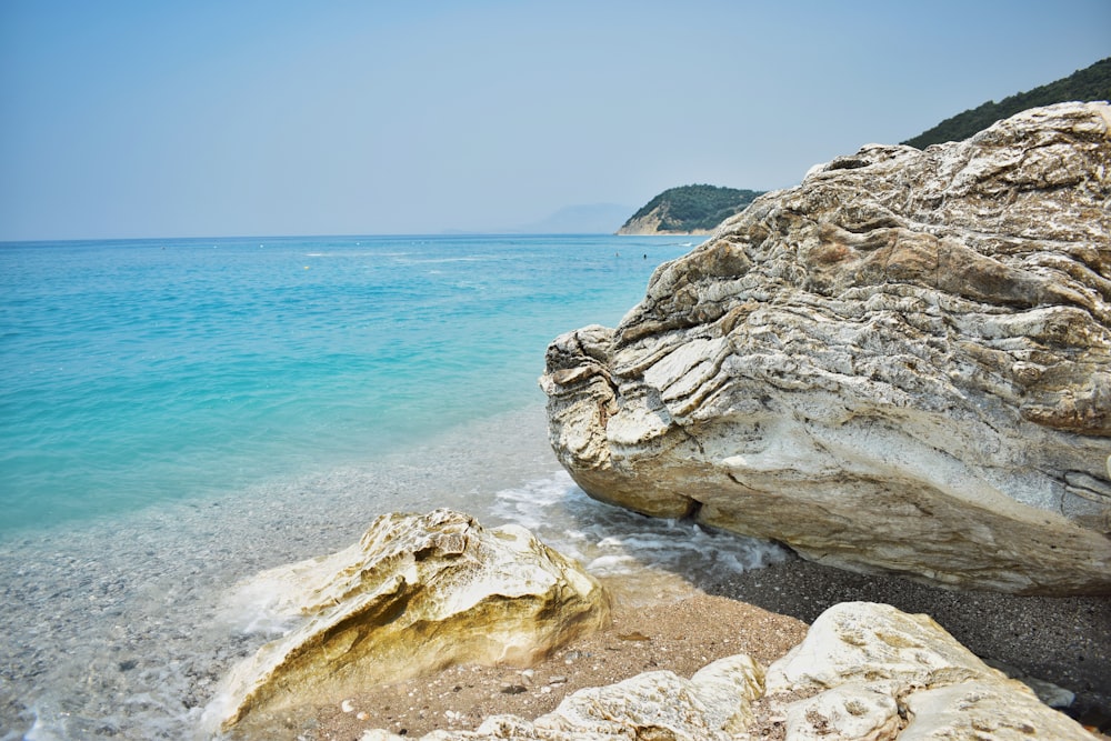 a large rock sitting on top of a beach next to the ocean