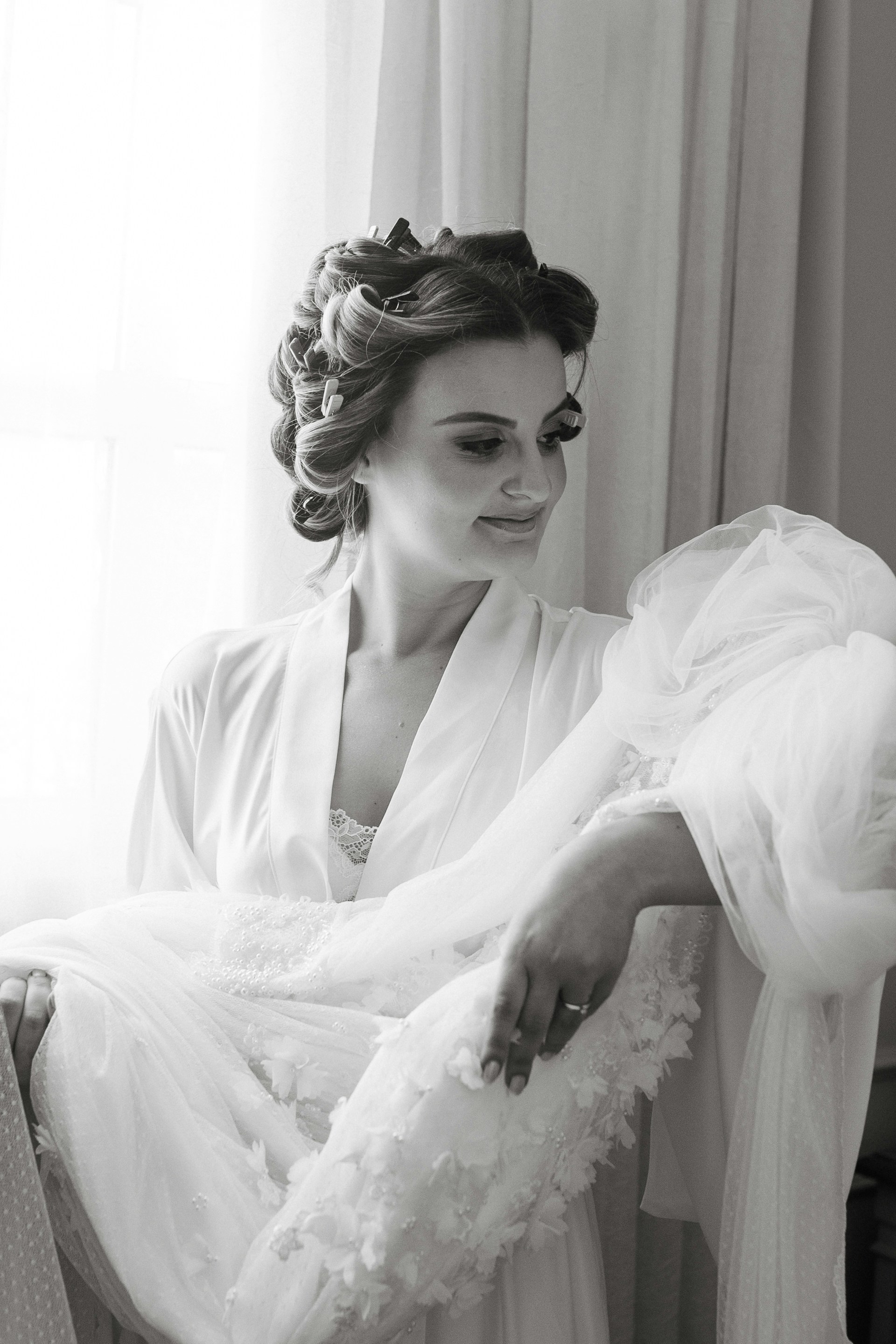 A friendly lady in branded uniform smiling warmly while holding freshly cleaned, perfectly pressed garments, embodying attentive customer service.