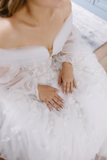 A crisp black-and-white shot capturing the delicate hands of a bride adjusting her lace sleeve