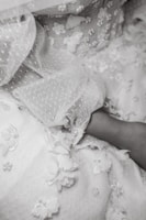Close-up of a flowing ivory bridal gown with delicate lace details on a soft beige background.