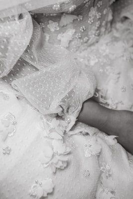 Close-up of intricate Victorian embroidery on a cream-colored dress, resting on textured kraft paper.