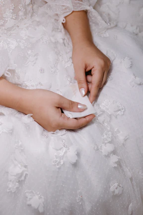 Close-up of delicate hands resting gracefully on smooth fabric.