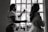 A stylist is preparing a woman for an event, possibly a wedding, by applying hairspray to her hairstyle. The setting is indoors with natural light coming through a window, casting silhouettes of both individuals. The woman wears an elaborate gown featuring lace and floral details.