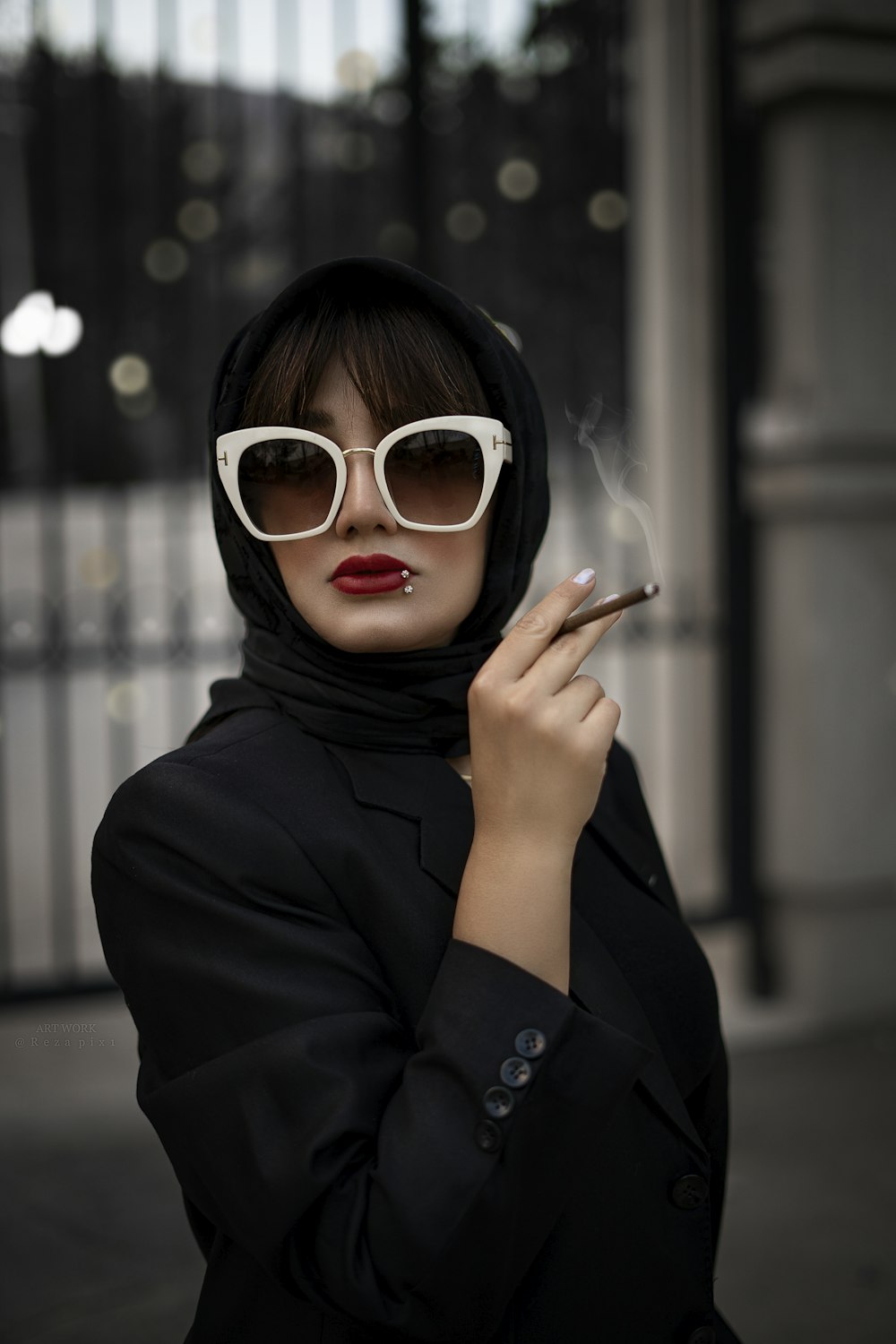 a woman in a black jacket and white sunglasses smoking a cigarette