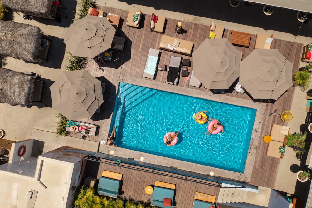 an aerial view of a pool with lounge chairs and umbrellas