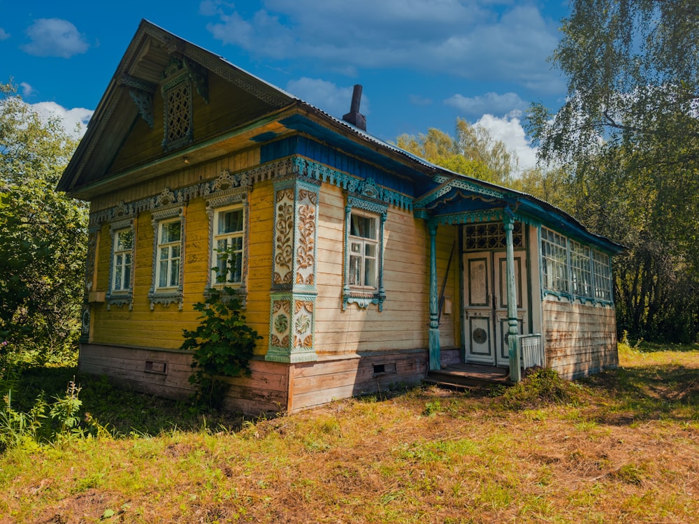 a yellow and blue house sitting in the middle of a field