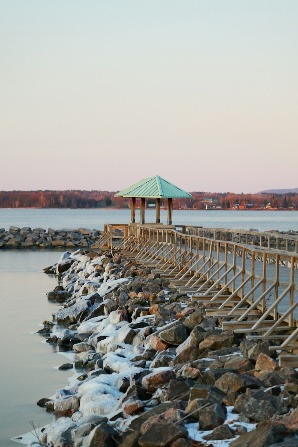 a wooden pier with a green roof next to a body of water