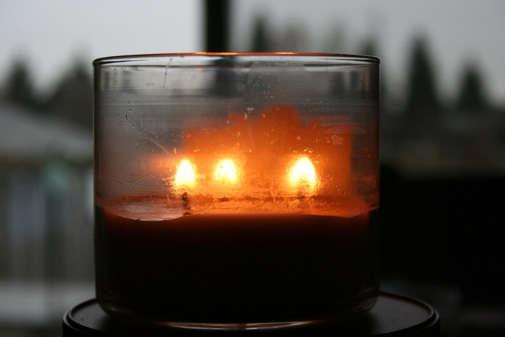 a lit candle is sitting in a glass
