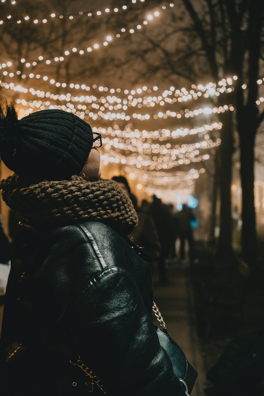 a woman wearing a beanie looking at a string of lights