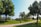 a path in a park with trees and a building in the background