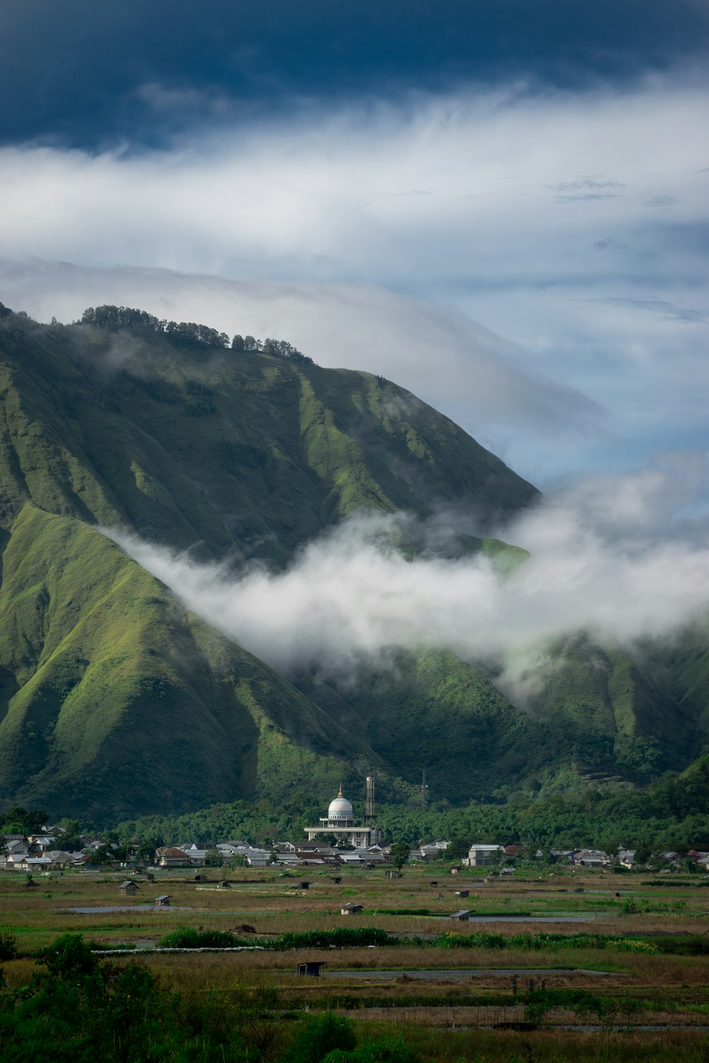 a mountain covered in clouds with a town in the foreground