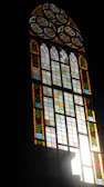 Close-up of a colorful stained glass window with intricate floral patterns glowing in sunlight.