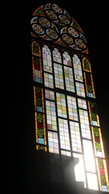 Close-up of a colorful stained glass window with intricate floral patterns glowing in sunlight.