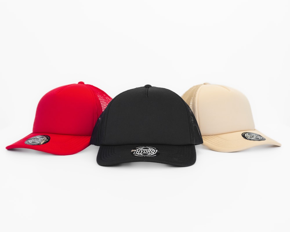 three different colored hats on a white background