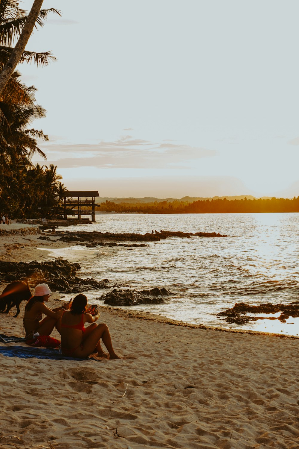 a couple of people sitting on top of a sandy beach