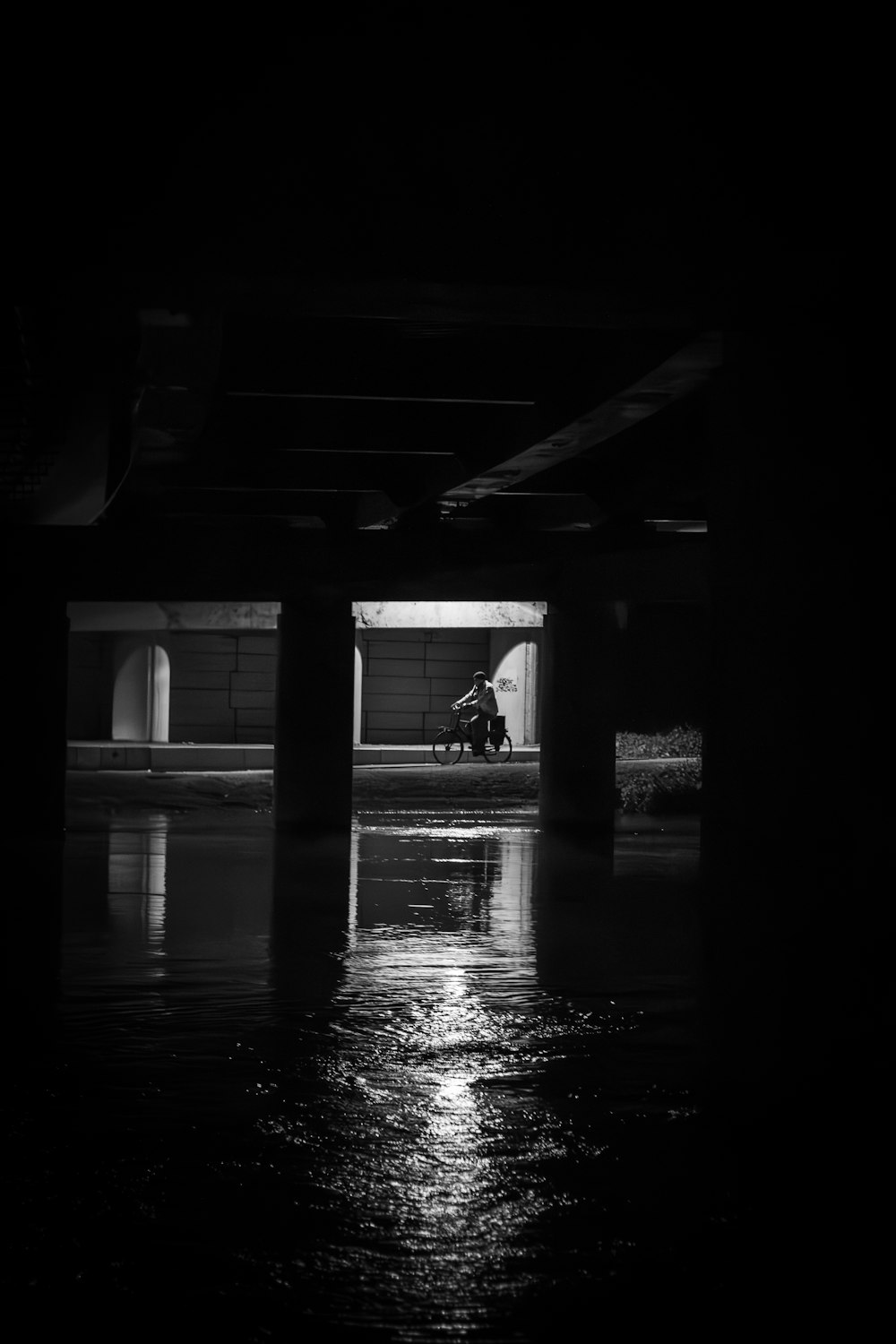 a person sitting on a bench under a bridge