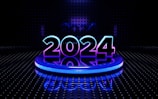 A futuristic setting featuring the glowing number 2024 prominently placed on a circular platform. The digits are illuminated with a blend of blue and purple hues. The background is a dark, perforated wall with a reflective floor that adds to the high-tech, digital aesthetic.
