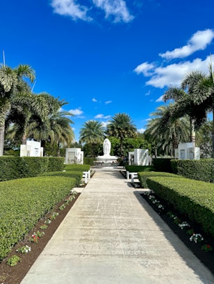 A serene garden path lined with blooming flowers and a small statue of St Joseph.