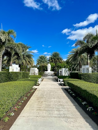 A serene garden path lined with blooming flowers and a small statue of St Joseph.