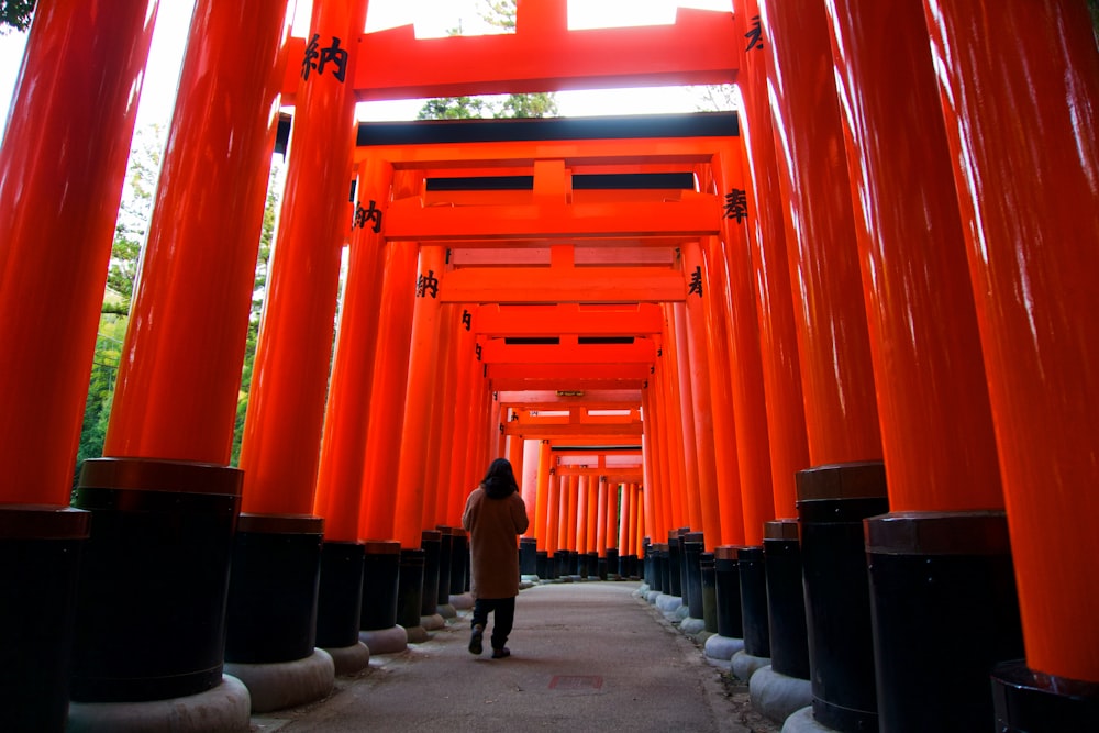 a person walking down a path lined with tall orange pillars