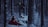 A mysterious forest scene with snow-covered ground and trees shrouded in darkness. A person in a red cloak is crouched on the ground, looking up at a figure in black with a mask standing on a snow-covered log. The forest creates a stark and tense atmosphere.
