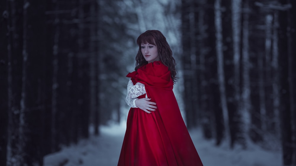 a woman in a red dress standing in the snow