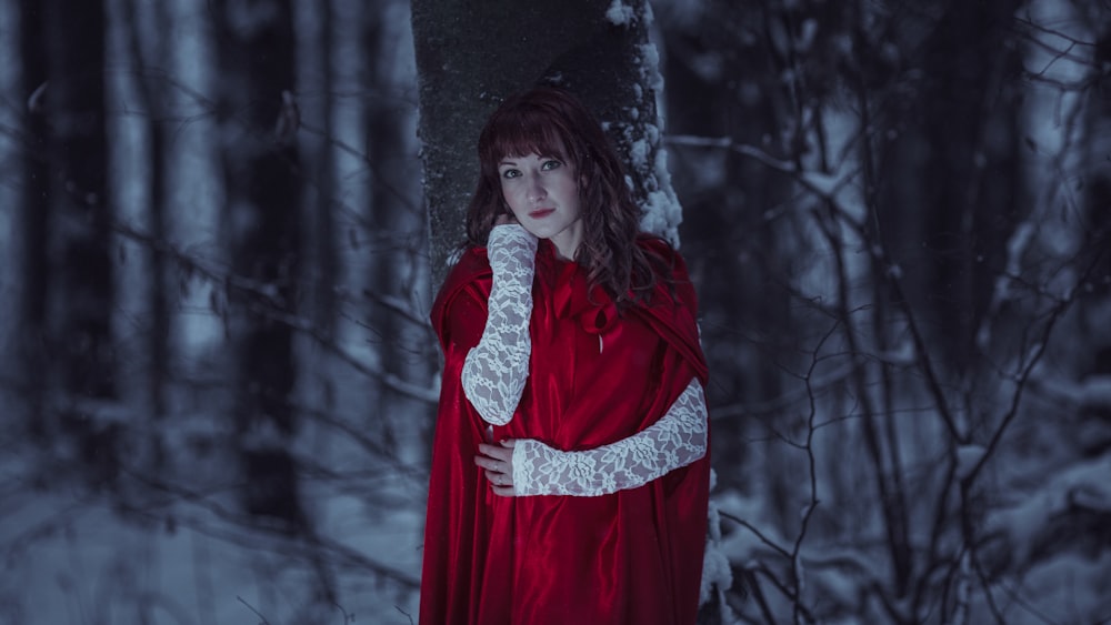 a woman in a red cloak standing in the snow