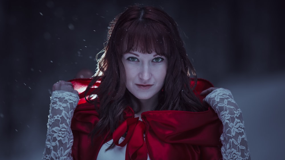 a woman wearing a red cape in a dark room