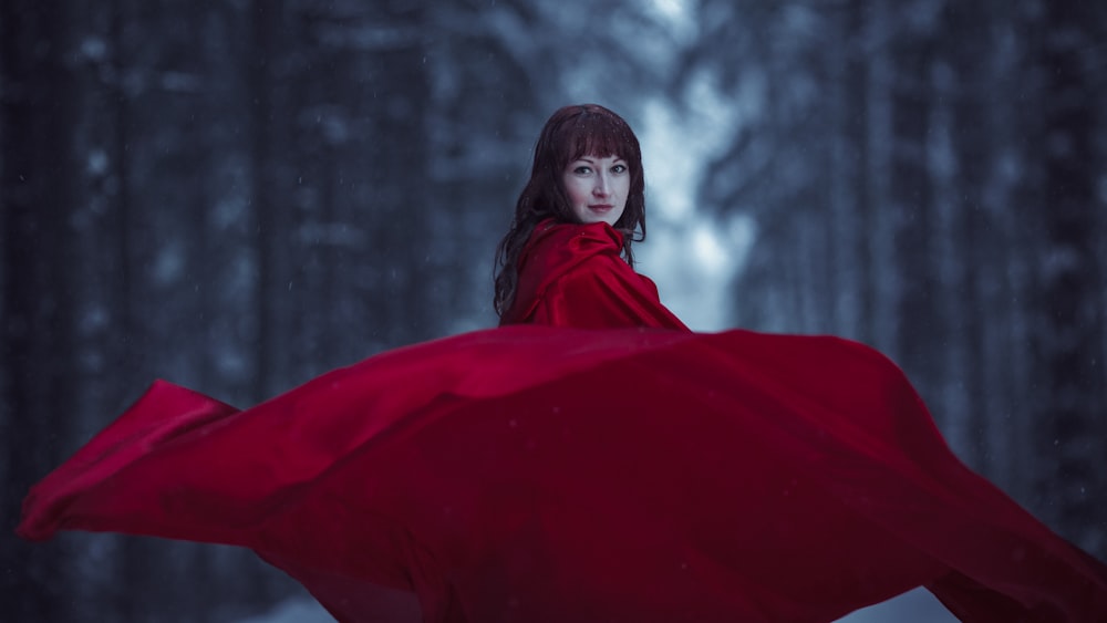 una mujer con una capa roja en un bosque nevado