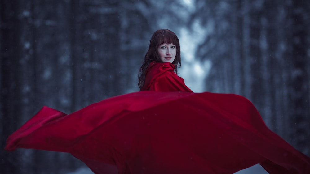 a woman in a red cloak in a snowy forest