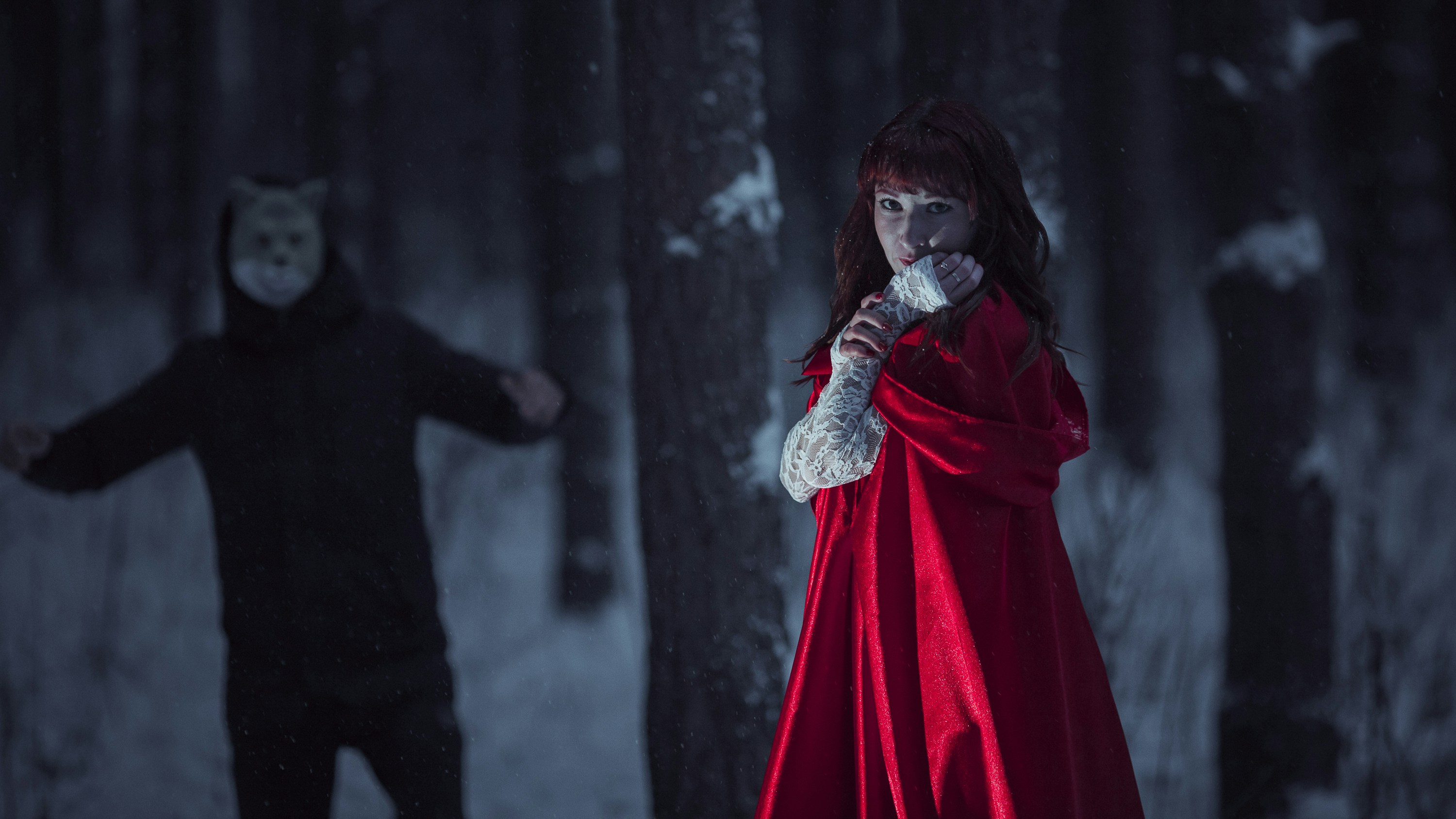 a woman in a red cloak standing next to a man in a black coat
