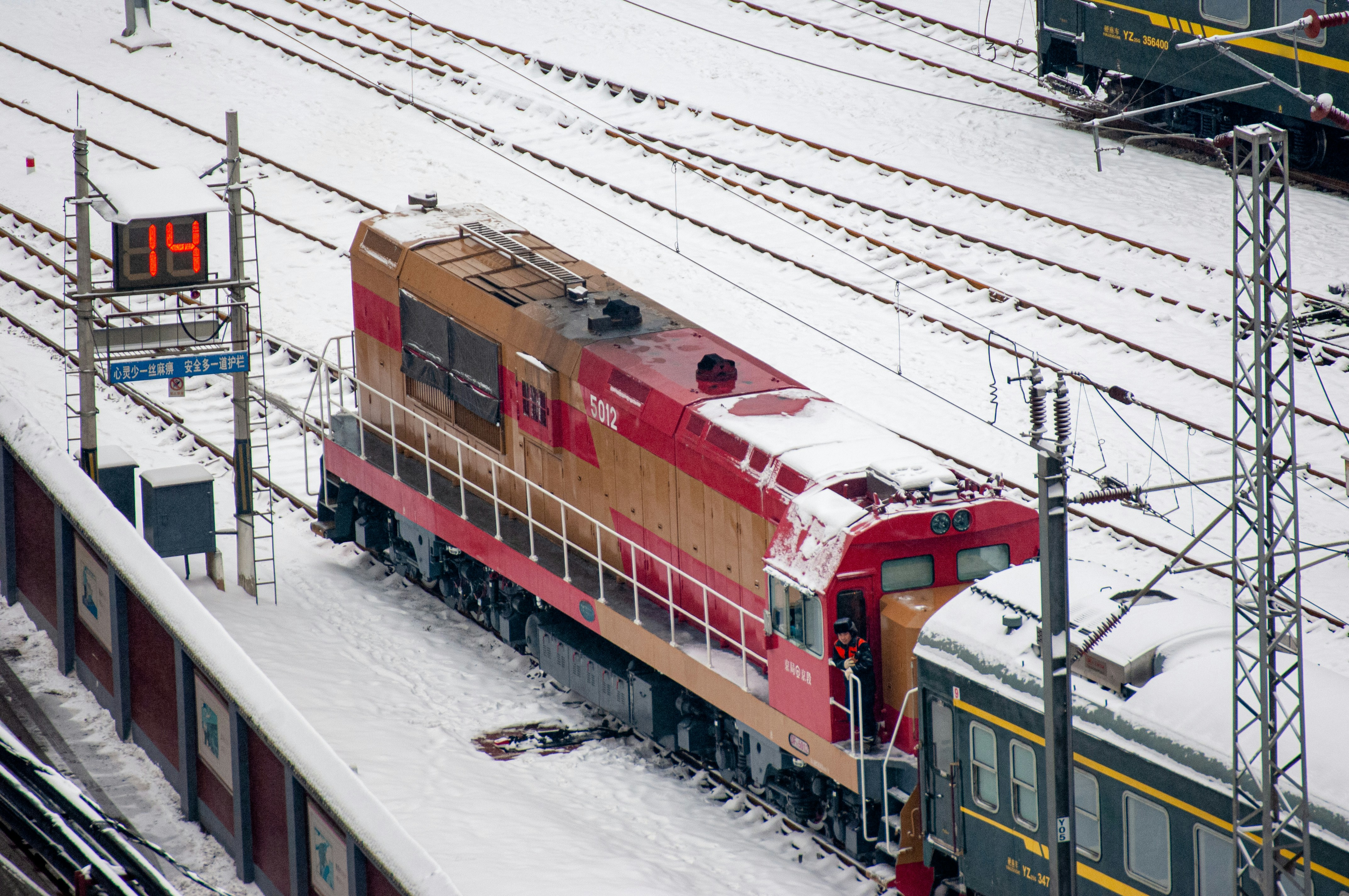 a red train traveling down train tracks next to snow covered ground