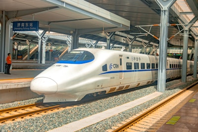 a white and blue bullet train pulling into a train station