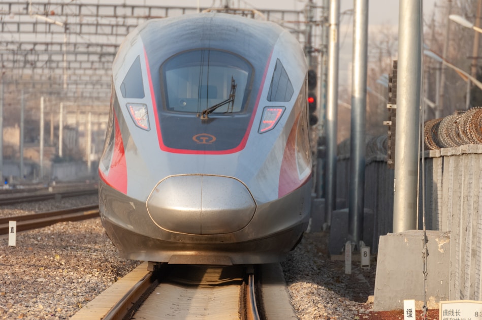a silver and red train traveling down train tracks