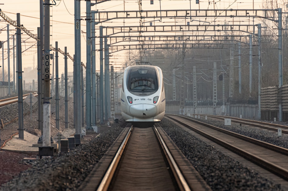 a white train traveling down train tracks next to tall buildings
