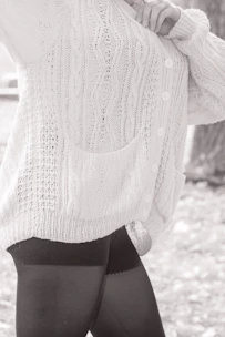 Close-up of soft knit cardigan in nude tones draped over a plus size model's shoulders.