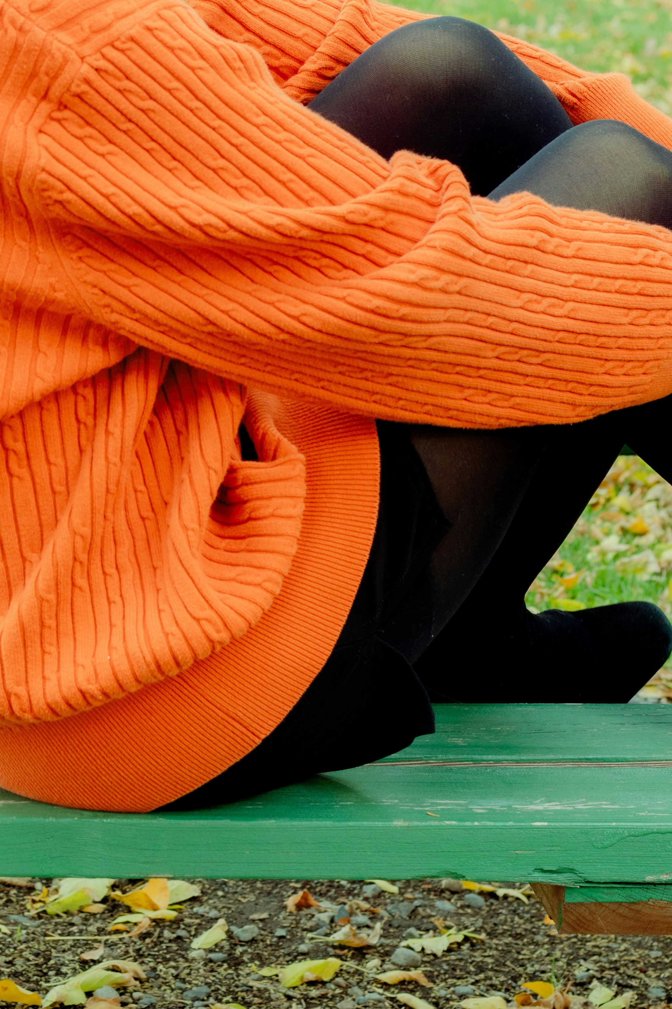 Person sitting bundled up in warm winter coat and mittens on bench outdoors cold weather