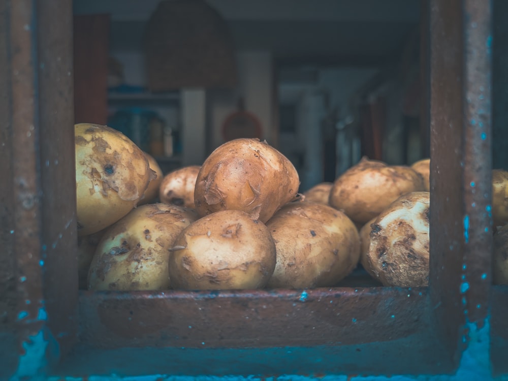 a pile of potatoes sitting on top of a wooden shelf