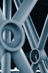 A close-up view of metallic pipes interconnected in a geometric structure, showcasing textures and circular joints.