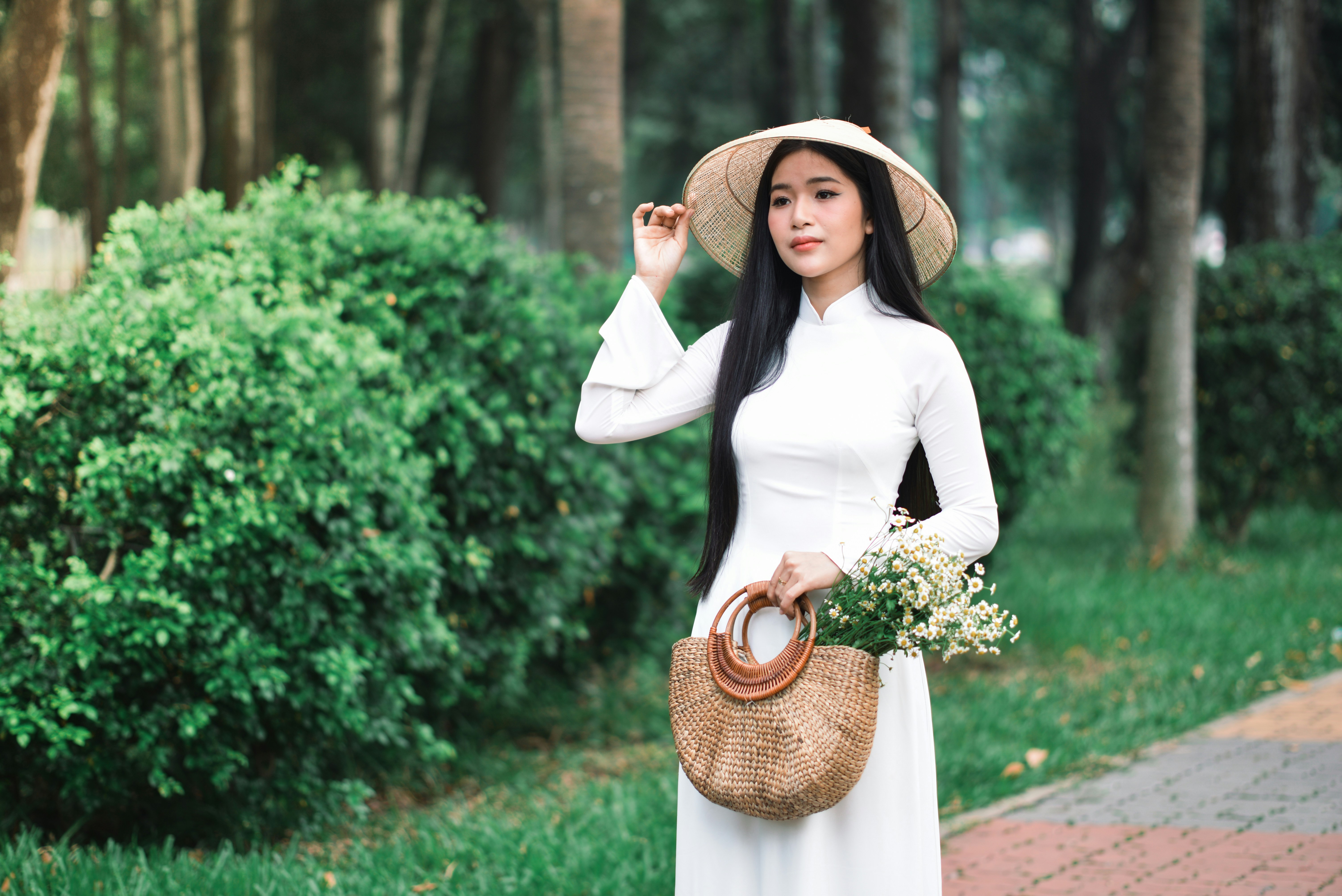 a woman in a white dress and hat holding a basket
