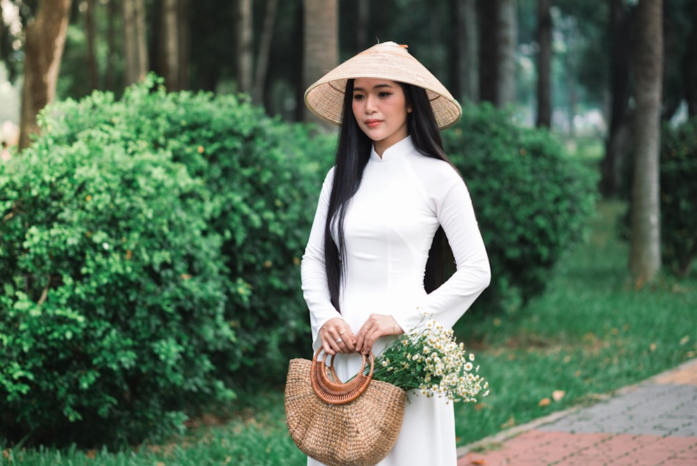 uma mulher usando um vestido branco e um chapéu de palha